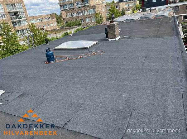 Bitumen dakbedekking op plat dak met lichtkoepel en schoorsteen in Hilvarenbeek