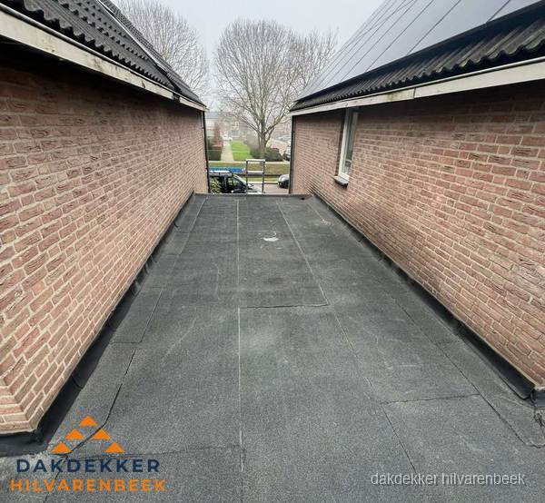 Plat dak met bitumen dakbedekking tussen bakstenen muren in Hilvarenbeek