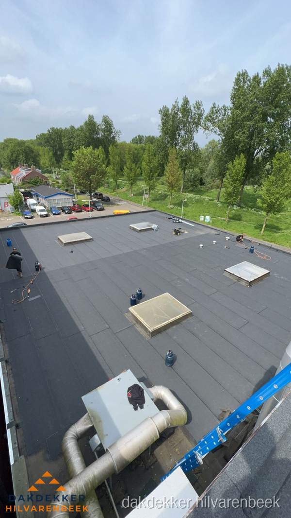 Dakdekker aan het werk op groot plat dak met bitumen in Hilvarenbeek Dakdekker aan het werk op groot plat dak met bitumen in Hilvarenbeek