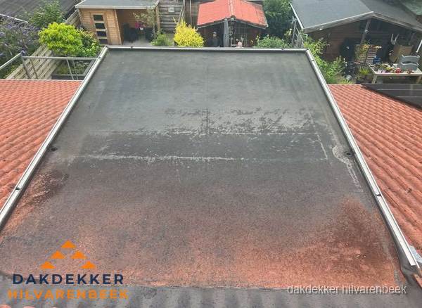 Verouderd plat dak met slijtage tussen schuine daken in Hilvarenbeek Verouderd plat dak met slijtage tussen schuine daken in Hilvarenbeek
