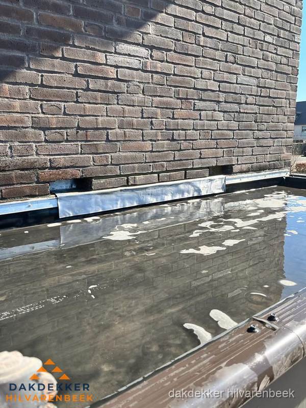 Stilstaand water op plat dak door slechte afwatering in Hilvarenbeek Stilstaand water op plat dak door slechte afwatering in Hilvarenbeek