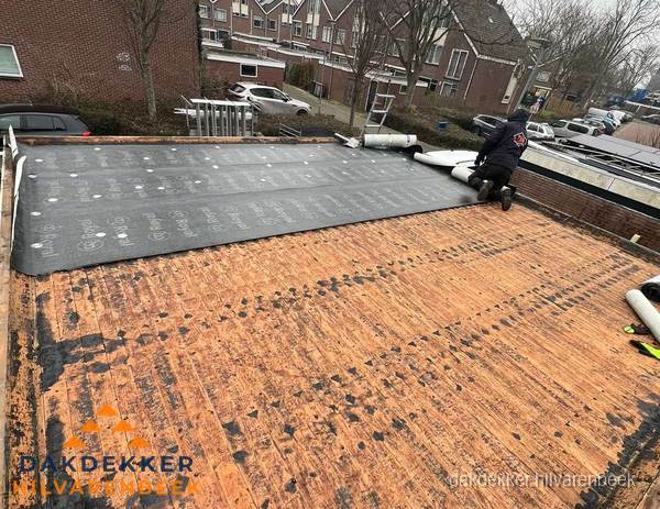 Dakdekker legt onderlaag op plat dak met houten constructie in Hilvarenbeek