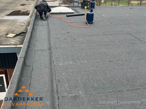 Dakdekker repareert bitumen dakbedekking op groot plat dak in Hilvarenbeek